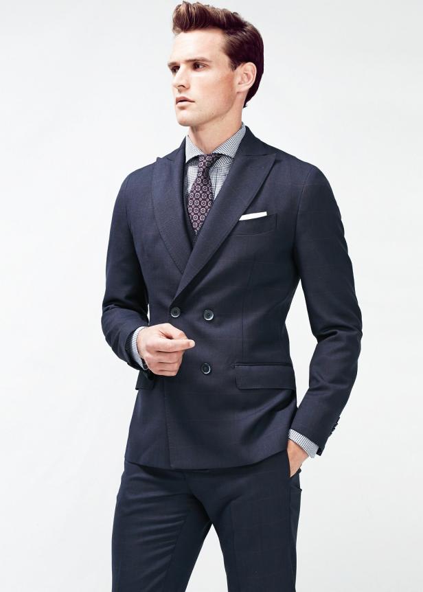 Ein Mann in einem eleganten, dunkelblauen Anzug mit Krawatte und Einstecktuch.