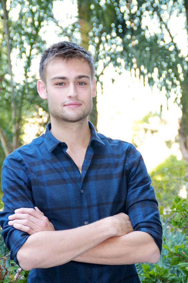 Ein Mann mit verschränkten Armen steht vor Bäumen.