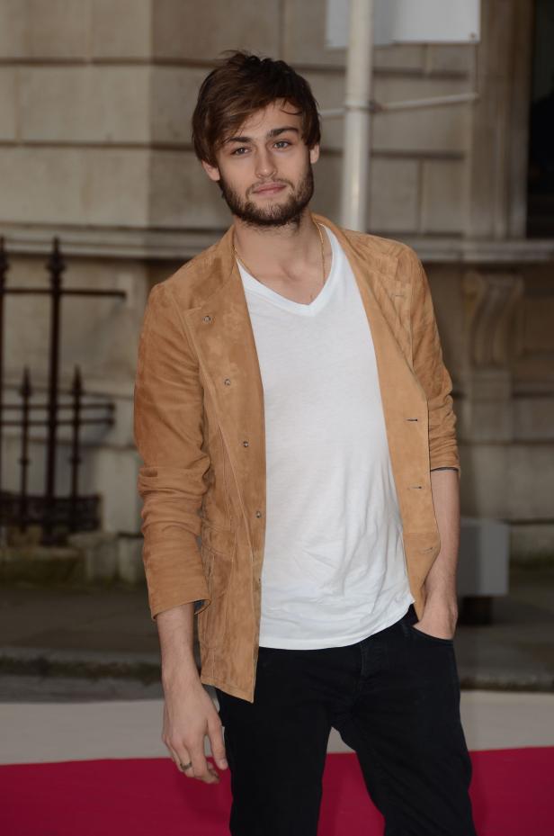 Douglas Booth posiert in einer hellbraunen Jacke und einem weißen T-Shirt.