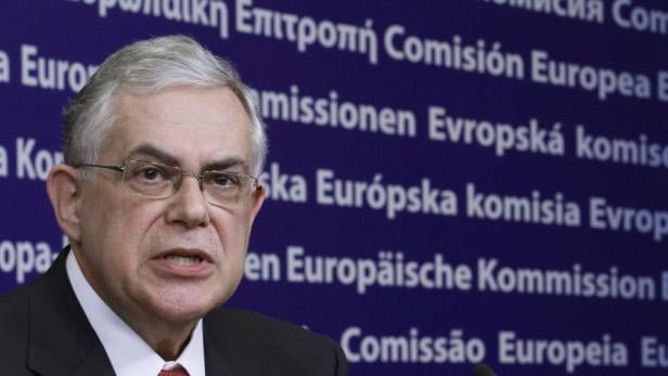 Ein Mann mit Brille spricht vor einem Hintergrund mit dem Schriftzug „Europäische Kommission“.