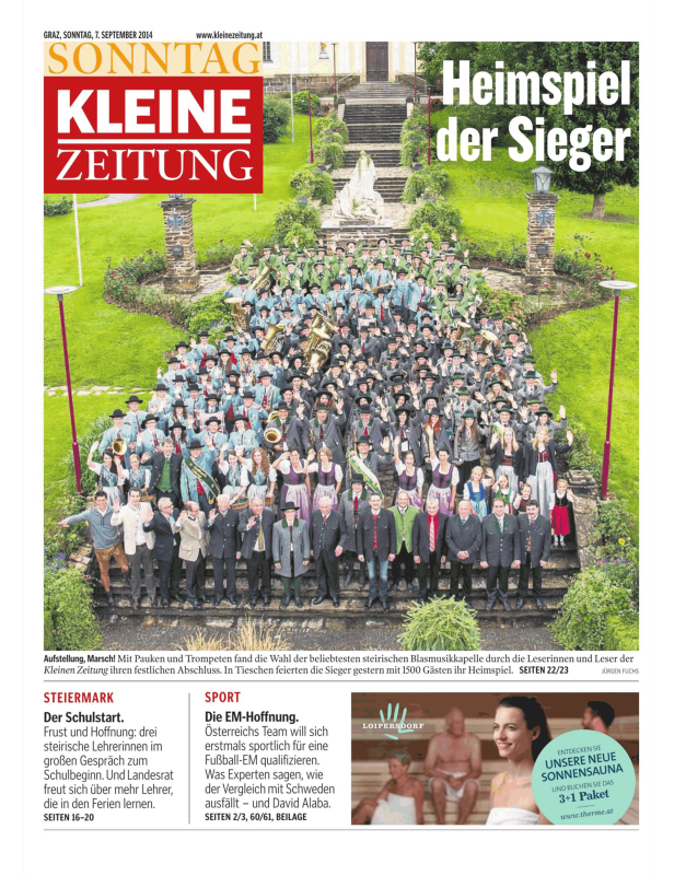 Eine große Blaskapelle der „Kleinen Zeitung“ posiert auf einer Treppe für ein Gruppenfoto.