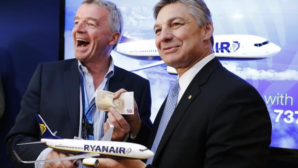 Zwei Männer halten ein Modellflugzeug von Ryanair und 50-Euro-Scheine.