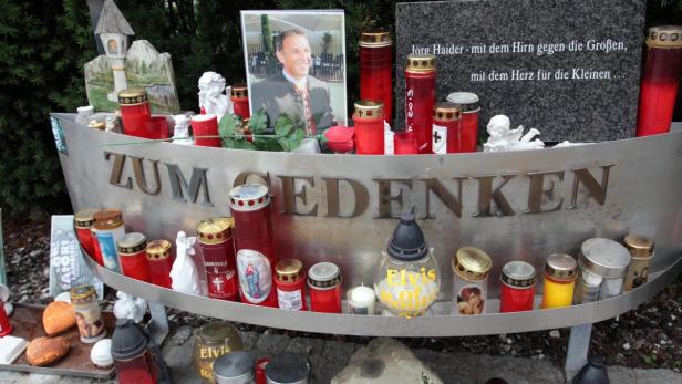 Eine Gedenkstätte für Jörg Haider mit Kerzen und einem Foto.