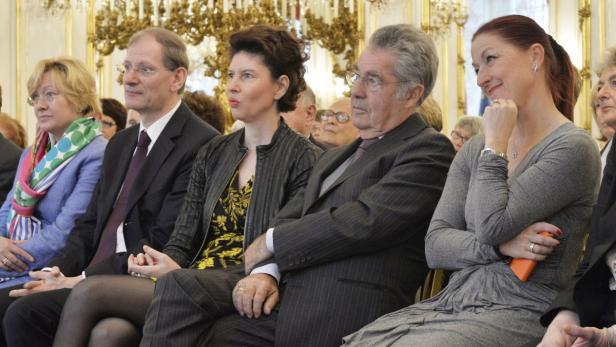 Eine Gruppe von Menschen sitzt bei einer Veranstaltung in einem eleganten Saal.