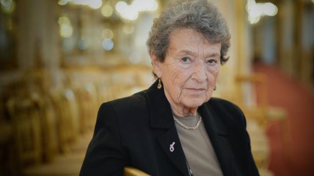 Eine ältere Frau mit grauen Haaren und einer schwarzen Jacke blickt in die Kamera.
