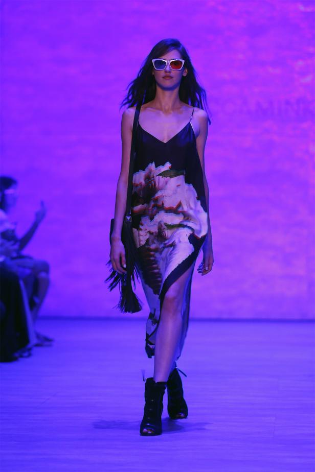 Eine Frau mit 3D-Brille läuft auf einem Laufsteg in einem Kleid mit Blumenmuster.