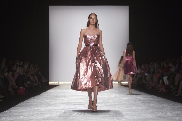 Eine Frau in einem trägerlosen, rosafarbenen Kleid auf einem Laufsteg.