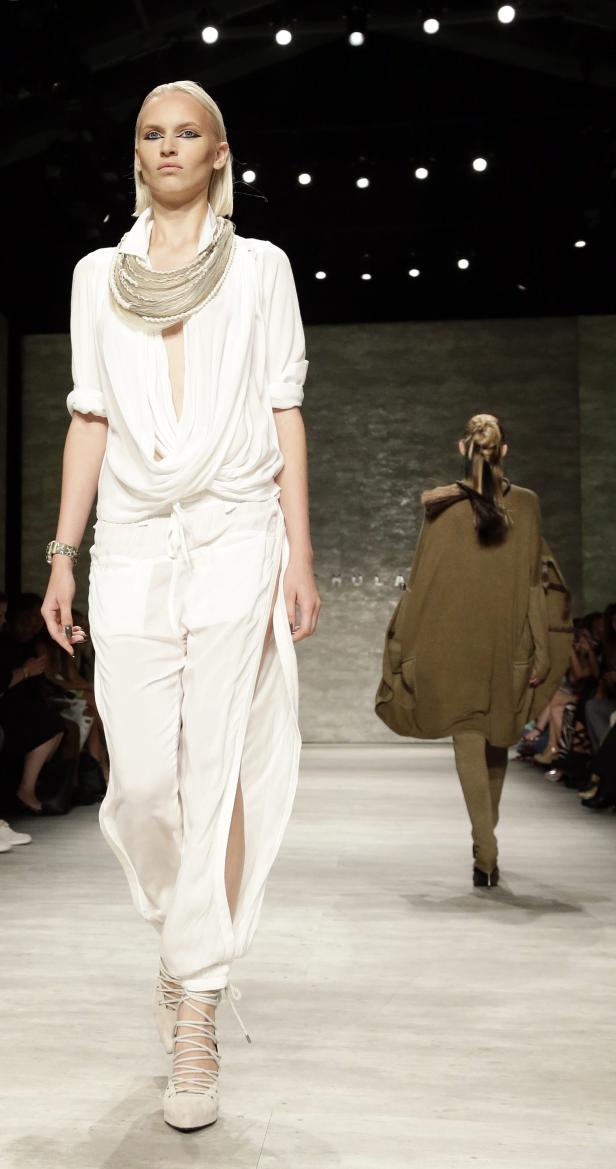 Eine Frau in weißer Kleidung läuft auf einem Laufsteg.