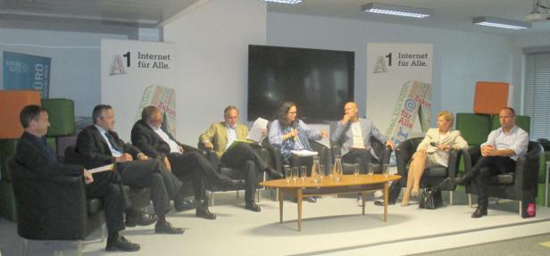 Eine Podiumsdiskussion mit mehreren Personen vor Bannern mit der Aufschrift „Internet für Alle“.