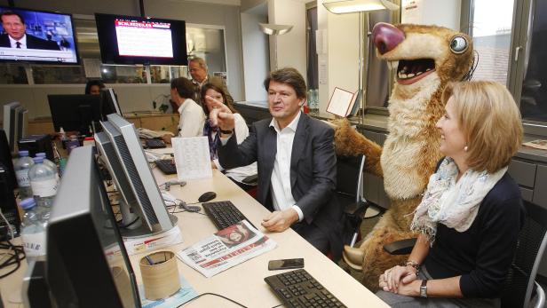 In einem Büro sitzt ein Mann mit einer Sid-Figur aus „Ice Age“.