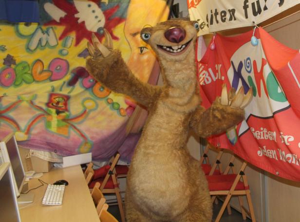 Ein lebensgroßes Sid-Faultier aus „Ice Age“ steht vor einem farbenfrohen Hintergrund.