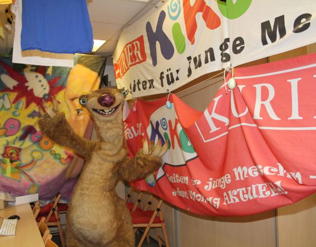 Eine Sid-Figur aus „Ice Age“ steht vor Bannern mit der Aufschrift „Kik“.