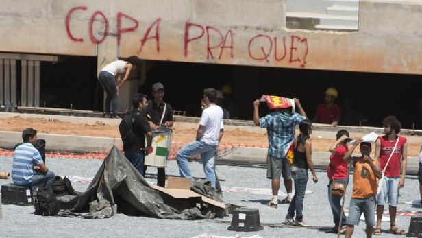 In Cuiabá wurde vorm Stadion die WM-Sinnfrage gestellt Eine Gruppe von Menschen demonstriert vor einem Gebäude mit der Aufschrift „Copa pra que?“.