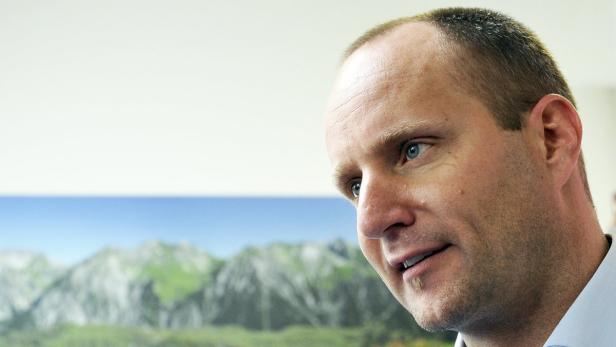 Ein Mann mit blauen Augen blickt vor einem Bergpanorama nach rechts.