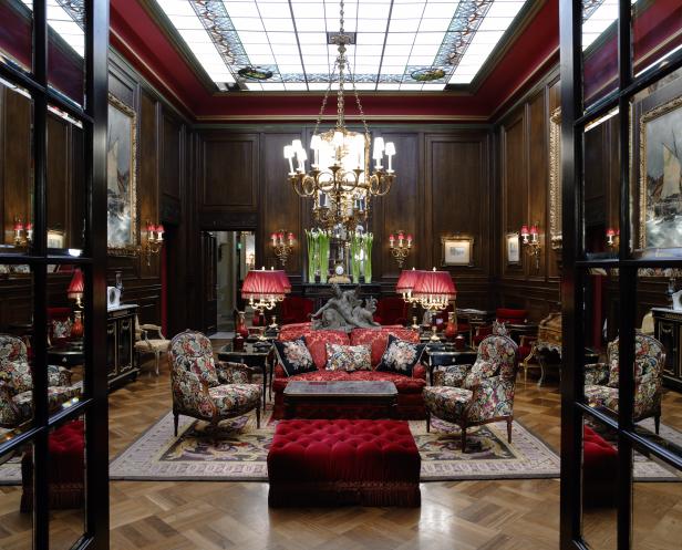 Ein opulent eingerichteter Salon mit dunklen Holzvertäfelungen und roter Dekoration.