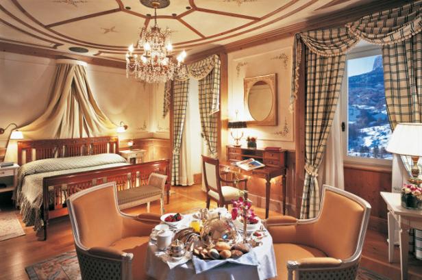 Ein luxuriöses Hotelzimmer mit Frühstück und Blick auf die verschneiten Berge.