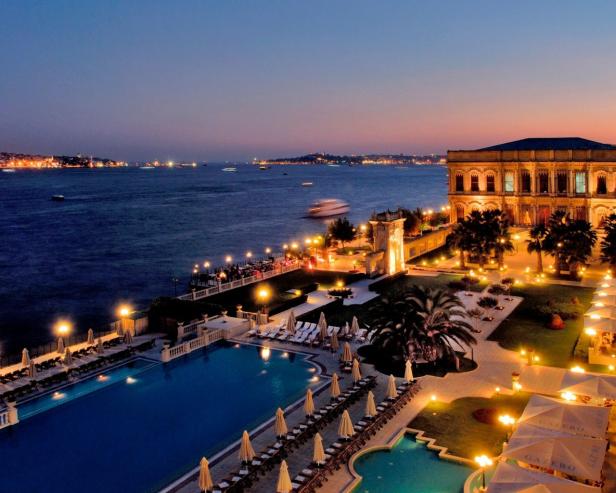 Das Çırağan-Palace-Hotel Kempinski in Istanbul bei Dämmerung mit Blick auf das Wasser.