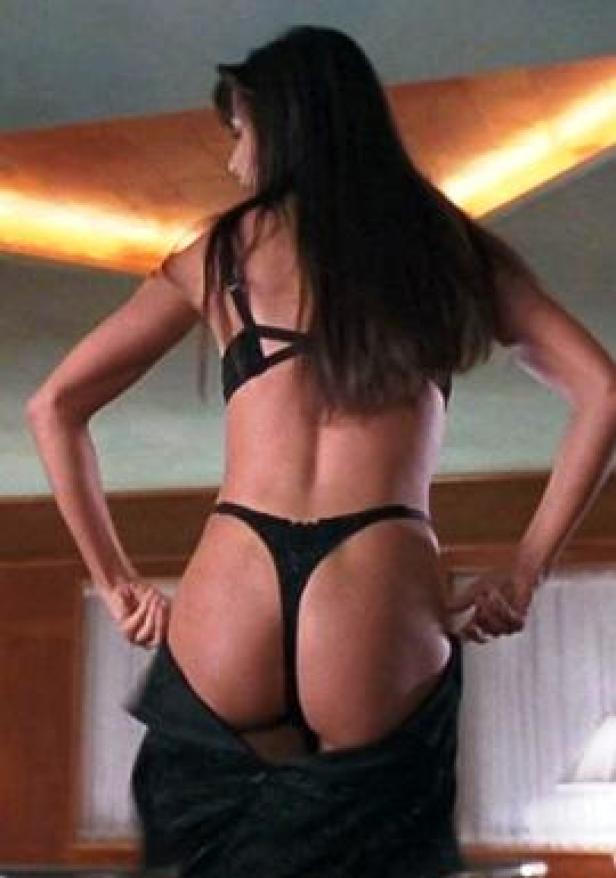 Eine Frau in Unterwäsche zieht ihre Hose aus.