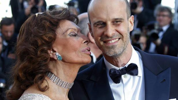 Sophia Loren flüstert einem Mann im Smoking etwas ins Ohr.