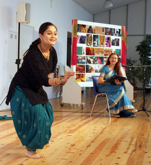 Eine Frau tanzt barfuß in traditioneller indischer Kleidung vor einem Publikum.