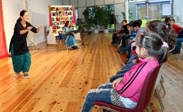 Eine Frau führt einen indischen Tanz vor einer Gruppe von Kindern auf.