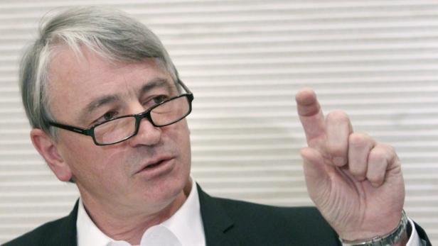 Ein Mann mit Brille gestikuliert mit erhobenem Zeigefinger.