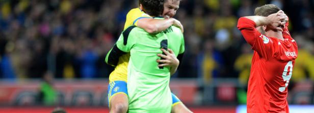 Kopie von WM-QUALIFIKATION: SCHWEDEN - ÖSTERREICH Zwei Fußballspieler umarmen sich, während ein dritter enttäuscht dasteht.