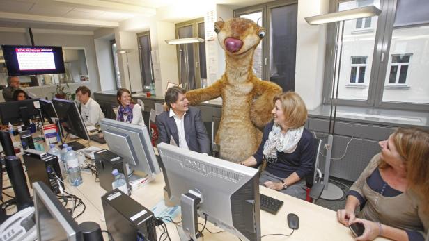 Sid aus „Ice Age“ steht in einem Büro und unterhält sich mit Mitarbeitern.