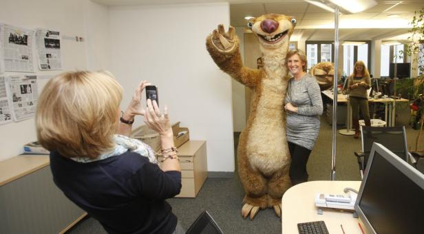 Eine Frau macht ein Foto von einer anderen Frau, die neben einer Sid-Figur aus „Ice Age“ steht.