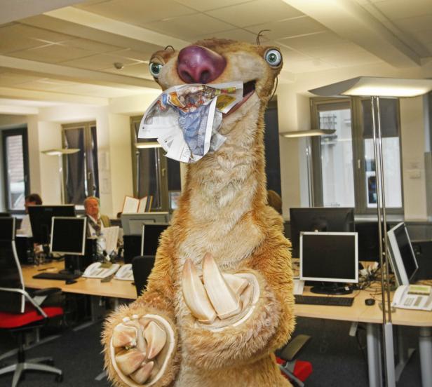 Ein Sid-Faultier-Kostüm steht in einem Büro und hat Papier im Maul.