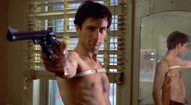 Robert De Niro als Travis Bickle in „Taxi Driver“ mit einer Waffe vor einem Spiegel.