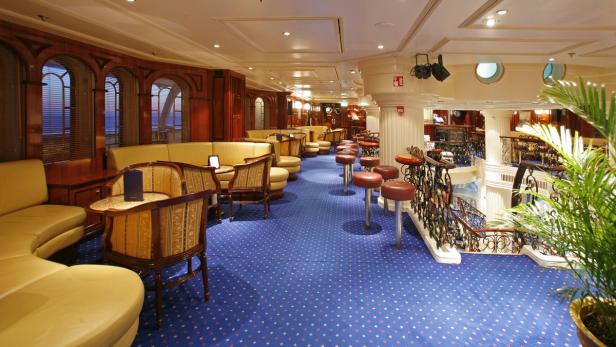 Ein luxuriöser Aufenthaltsraum mit Barhockern und Sitzgelegenheiten auf einem Kreuzfahrtschiff.