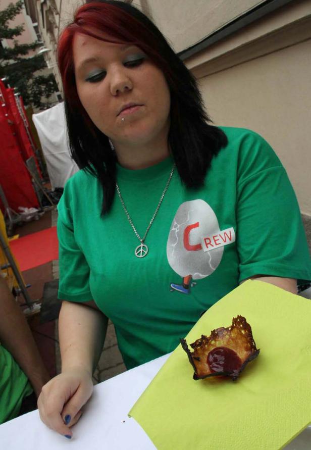 Eine Frau mit einem grünen T-Shirt isst etwas auf einer Serviette.