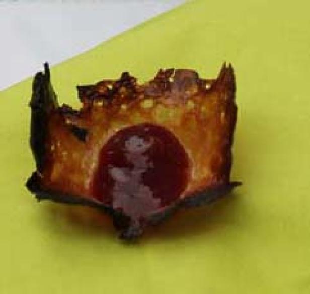 Ein verbrannter Crêpe mit roter Füllung liegt auf einem gelben Tuch.