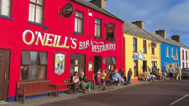 Bunte Häuserfassaden mit Menschen vor „O'Neill's Bar & Restaurant“ in Irland.