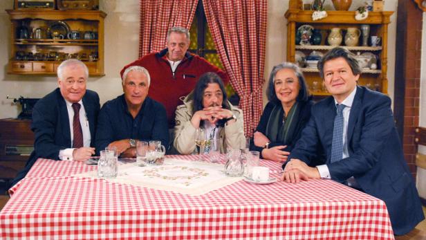 Eine Gruppe von sechs Personen sitzt an einem Tisch mit rot-weiß karierter Tischdecke.