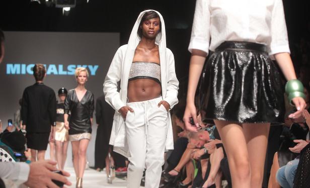 Ein Model in weißem Trainingsanzug auf dem Laufsteg einer Michalsky-Show.