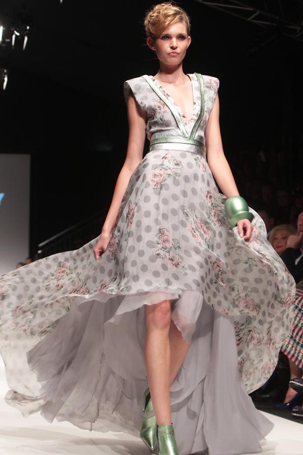 Eine Frau präsentiert ein graues Kleid mit Blumenmuster auf dem Laufsteg.