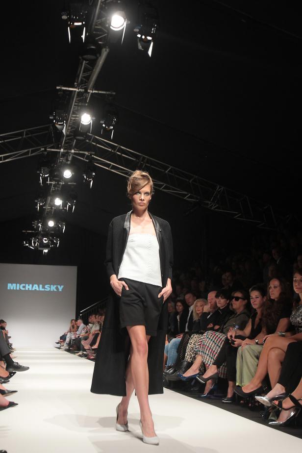 Ein Model präsentiert Mode von Michalsky auf dem Laufsteg vor Publikum.