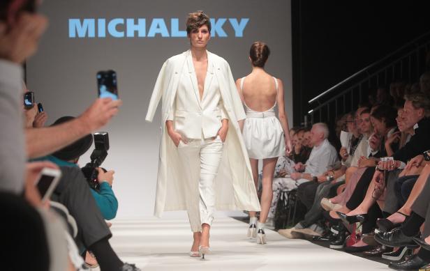 Eine Frau in einem weißen Hosenanzug auf dem Laufsteg bei einer Modenschau von Michalsky.