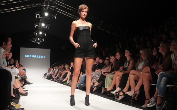 Eine Frau präsentiert Mode von Michalsky auf dem Laufsteg vor Publikum.