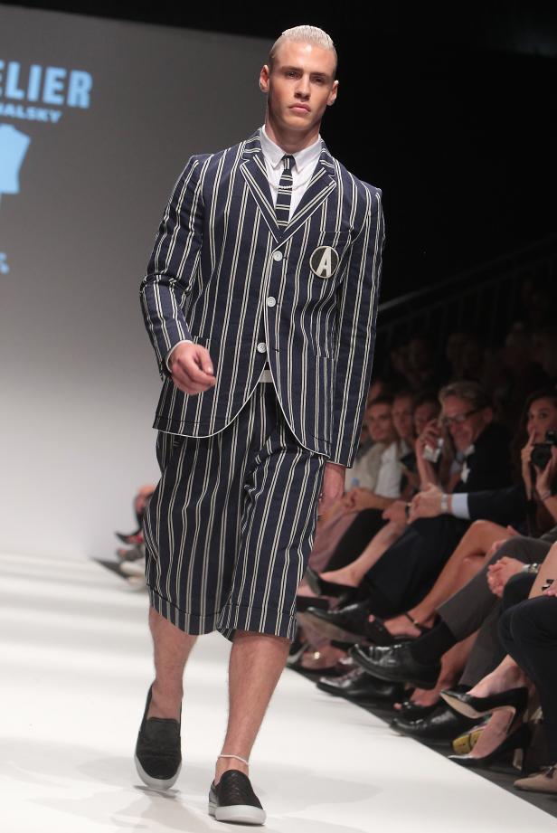Ein Mann präsentiert ein gestreiftes Anzug- und Shorts-Set auf einem Laufsteg.