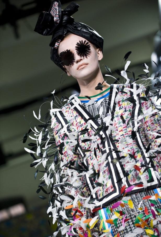 Ein Model mit floraler Brille und extravaganten Federn auf dem Laufsteg.