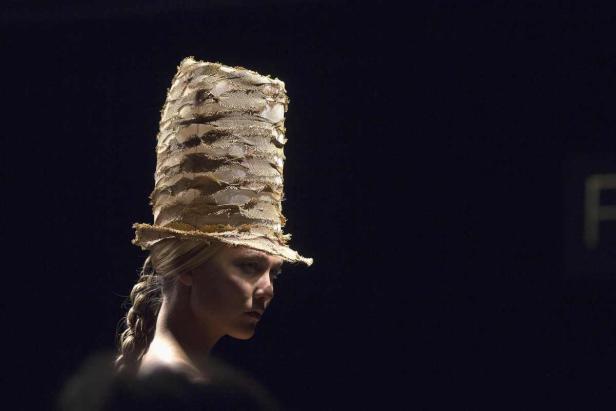 Eine Frau mit blonden Zöpfen trägt einen hohen, ungewöhnlichen Hut.