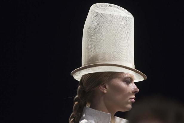 Eine Frau trägt einen hohen, weißen Zylinderhut.