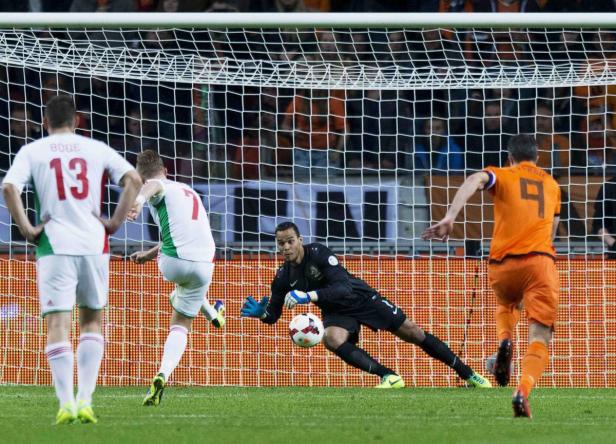 Ein Fußballspieler schießt einen Elfmeter, während der Torwart versucht, den Ball abzuwehren.