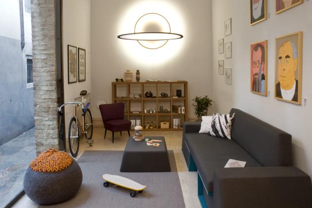 Ein Wohnzimmer mit einem grauen Sofa, einem Hocker und einem Skateboard.