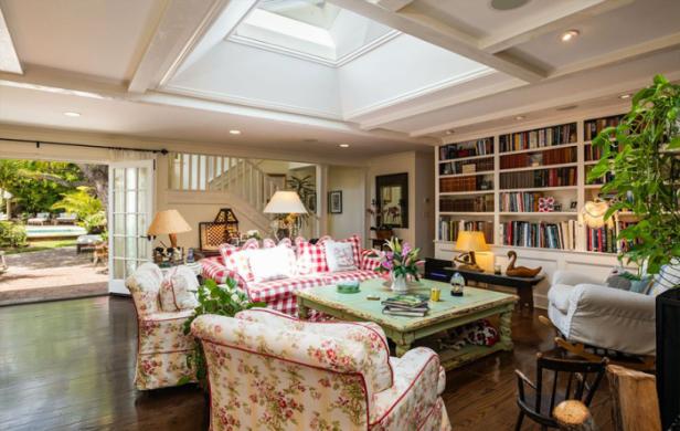 Ein Wohnzimmer mit floralen Sesseln, einem rot-weiß karierten Sofa und einem Bücherregal.