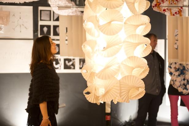 Eine Frau betrachtet eine leuchtende, spiralförmige Papierinstallation.
