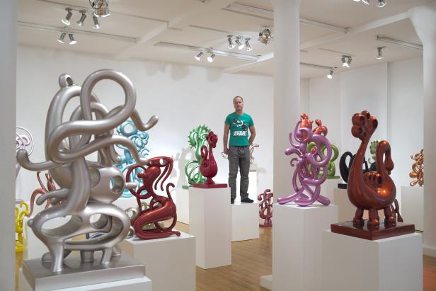 Ein Mann steht in einer Galerie mit bunten, abstrakten Skulpturen.